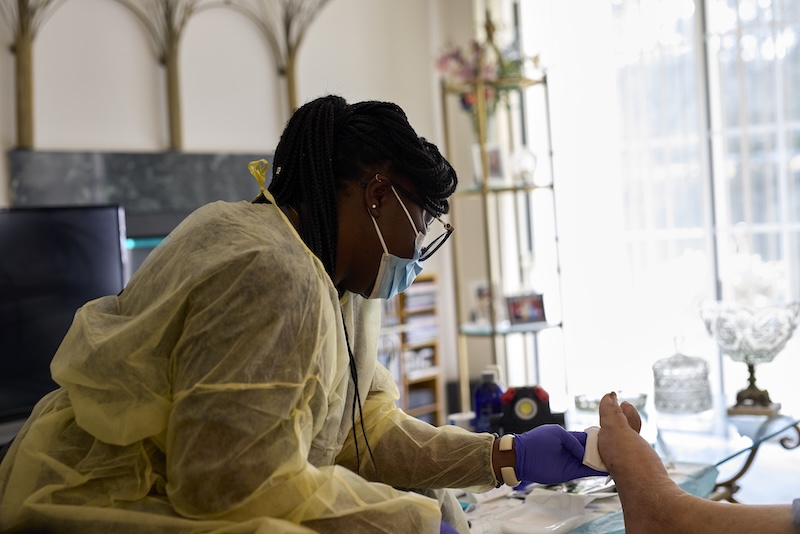 nurse treating a patient's foot ulcer in the patient's home